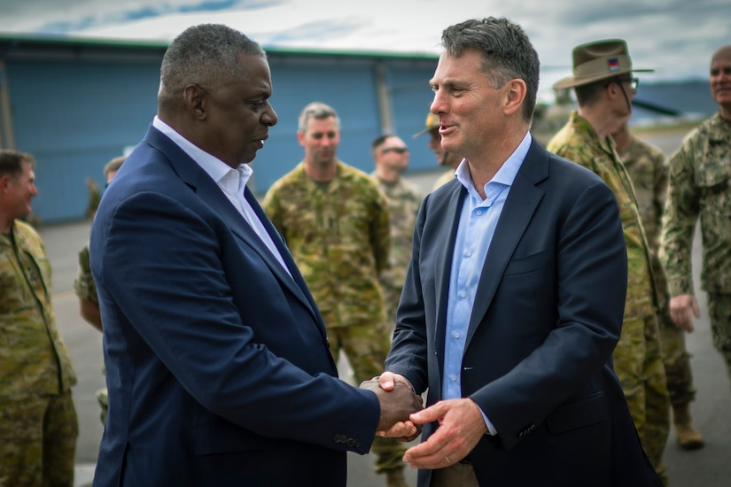 Australian and U.S. military leaders shake hands during Exercise Talisman Sabre, highlighting international cooperation.