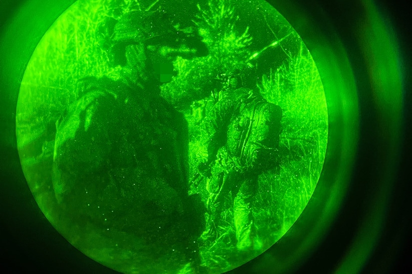 NATO service members in standard issue NATO uniform providing security during a night operation, highlighting readiness and interoperability.