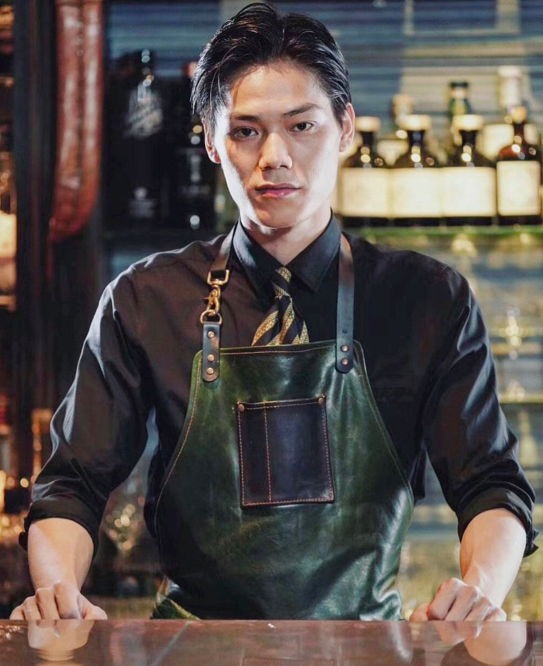 Bartender at Speak Low Shanghai in a vest, leather apron, and tie, evoking French Concession-era speakeasy style for bartender uniforms.