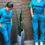 Two nurses leaning against a wall modeling nursing scrubs Uniform Advantage Butter-Soft Stretch scrubs review