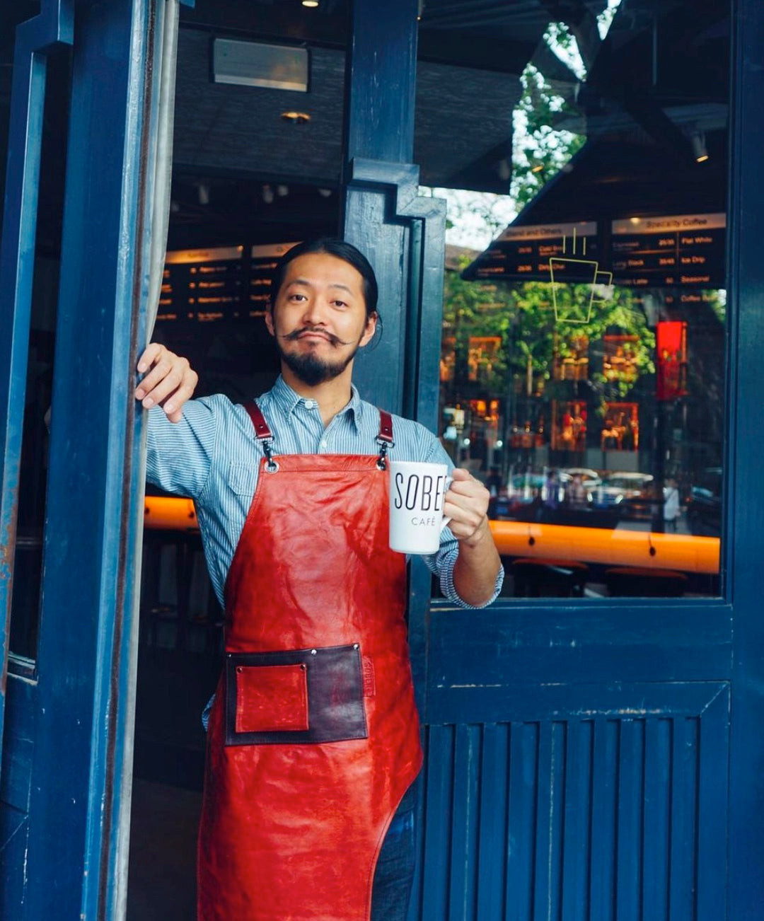 Bartender at Sober Company Shanghai in a black dress shirt and leather apron, showcasing sophisticated and quirky uniform variety.