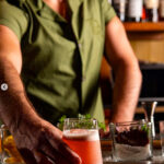 Bartenders in green Irish-inspired uniforms at The Dead Rabbit, New York, showcasing Celtic heritage.