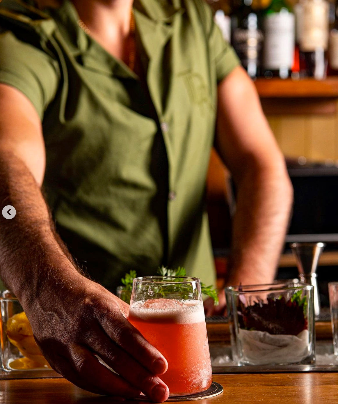 Bartenders in green Irish-inspired uniforms at The Dead Rabbit, New York, showcasing Celtic heritage.