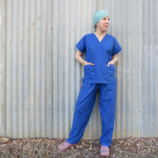 A person in blue scrub uniform patterns, demonstrating the fit and style of the free design.