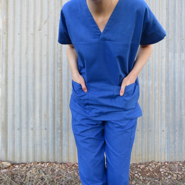 Two people wearing handmade scrub uniform patterns in blue, showcasing the design and fit.