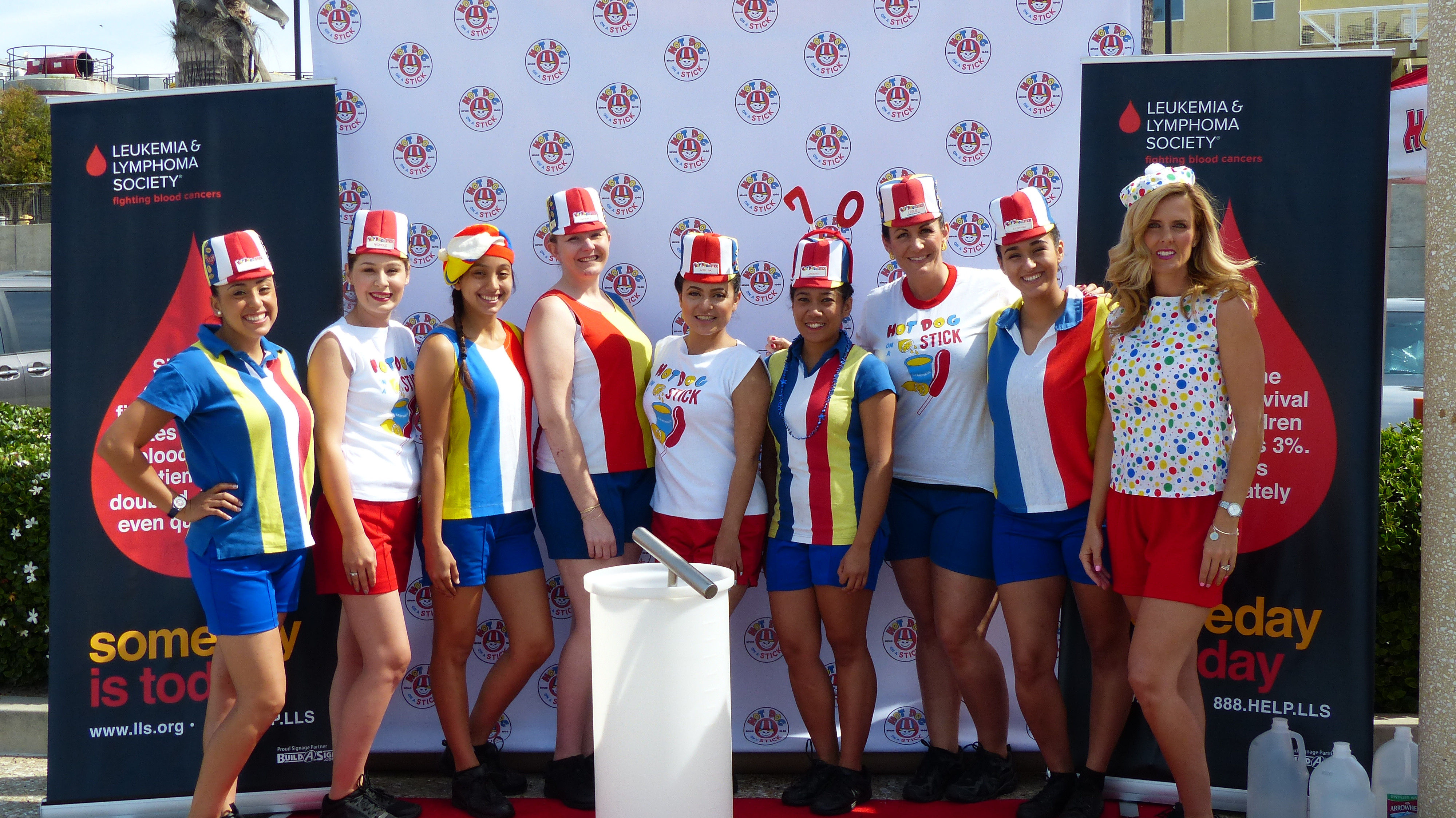 A group of Hotdogger employees proudly displaying the red, white, and blue striped uniforms, a symbol of the Hot Dog on a Stick brand