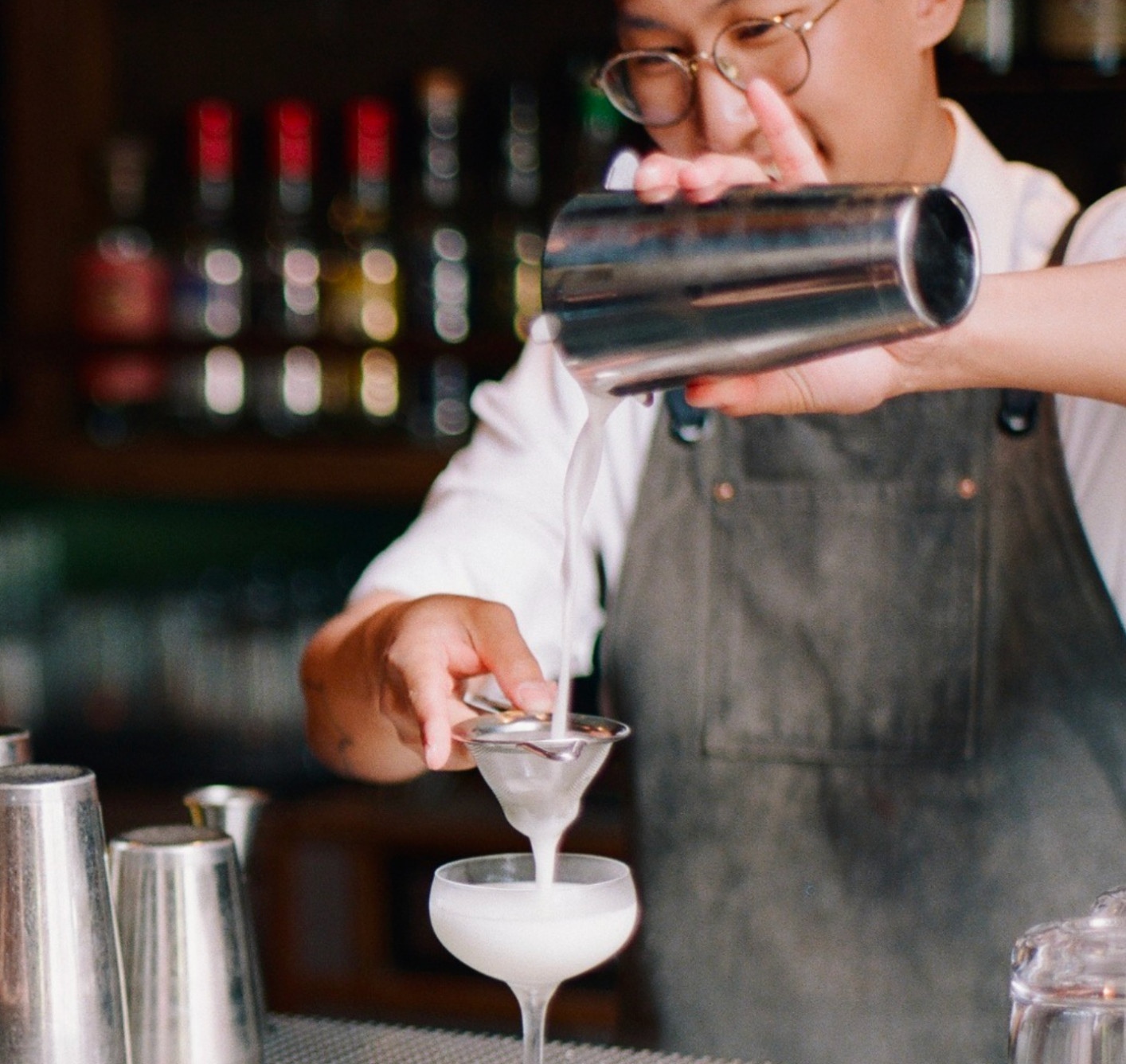 Another view of Trick Dog bartender uniform flexibility, highlighting the range from tees to dress shirts paired with denim aprons.