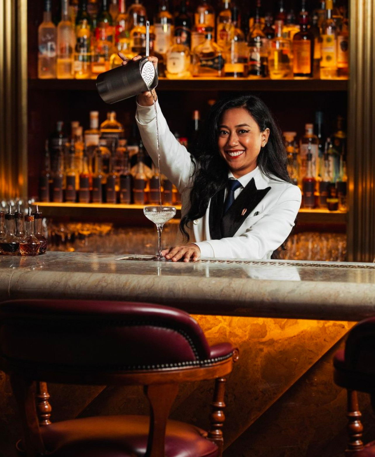 Bartender at Atlas Singapore in a crisp white shirt and double-breasted suit, exemplifying Art Deco elegance in bartender attire.