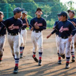 Youth softball player sliding into base covered in dirt