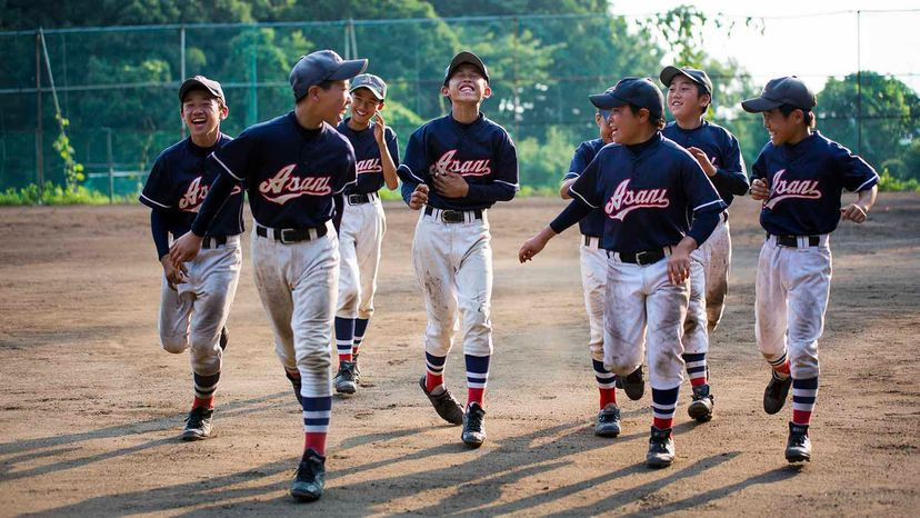 Youth softball player sliding into base covered in dirt